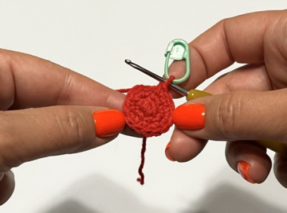 Image of hands holding a crochet work with a stitch marker